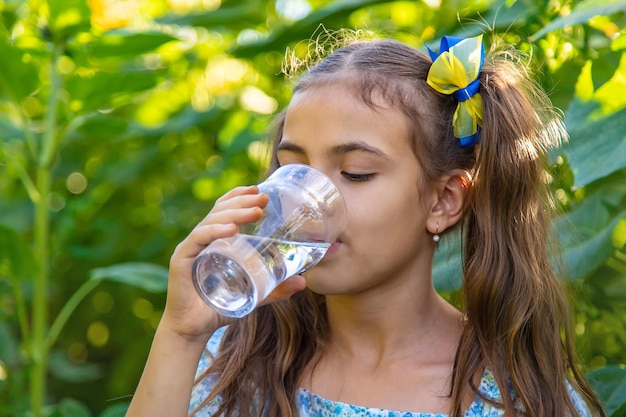 Il bambino beve l'acqua da un bicchiere Messa a fuoco selettiva