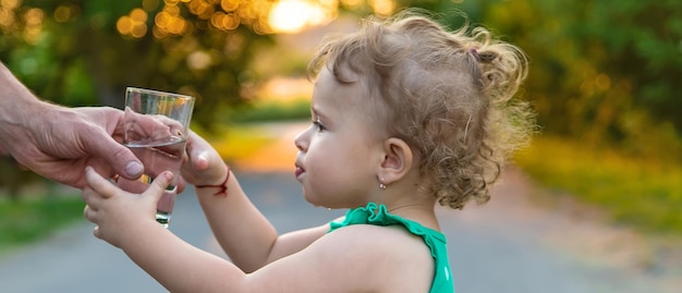 Il bambino beve l'acqua da un bicchiere Messa a fuoco selettiva