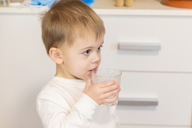 Il bambino beve l'acqua da un bicchiere