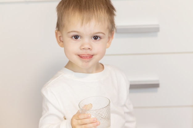 Il bambino beve l'acqua da un bicchiere