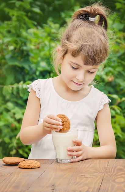 Il bambino beve latte e biscotti. Messa a fuoco selettiva