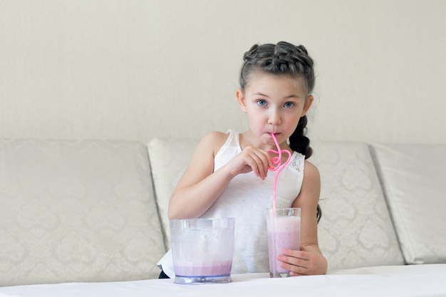 Il bambino beve un cocktail con una cannuccia.