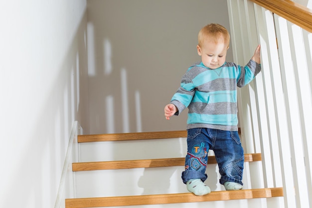 Il bambino biondo sulle scale Il ragazzo scende con cautela le scale di casa