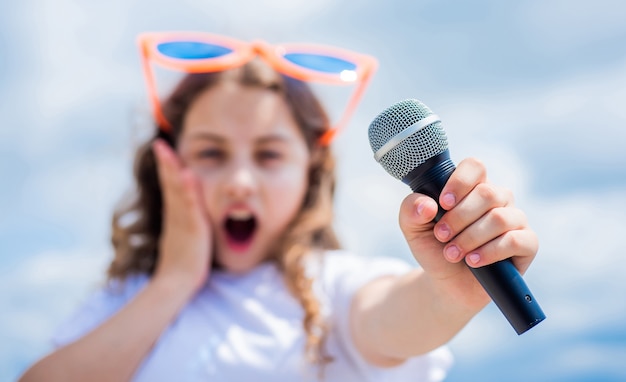 Il bambino canta con il microfono. messa a fuoco selettiva. allegro organizzatore di eventi. il bambino si diverte alla festa. cantante felice con microfono. classico fresco. ragazza che canta. concetto di scuola vocale. club di karaoke. la musica è la mia vita.