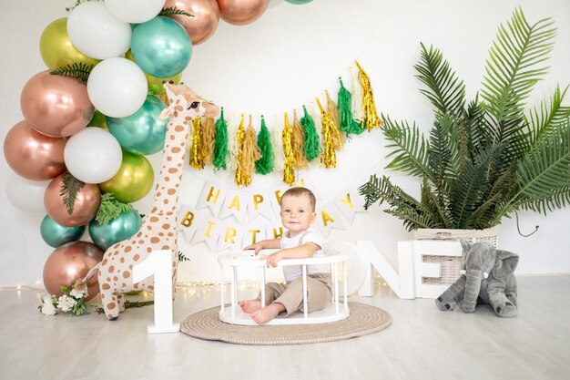 Il bambino carino festeggia il suo primo compleanno sullo sfondo di palloncini colorati luminosi e oggetti di scena festivi la prima vacanza per bambini