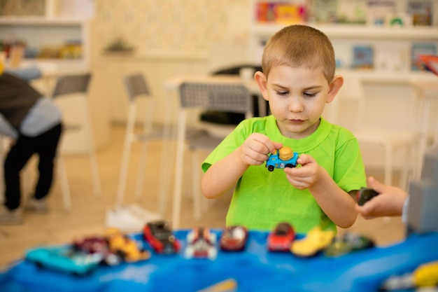 Il bambino carino sta giocando con le macchinine a casa