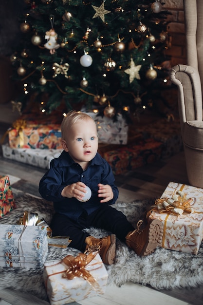 Il bambino caucasico felice si siede nell'atmosfera e nei sorrisi di natale