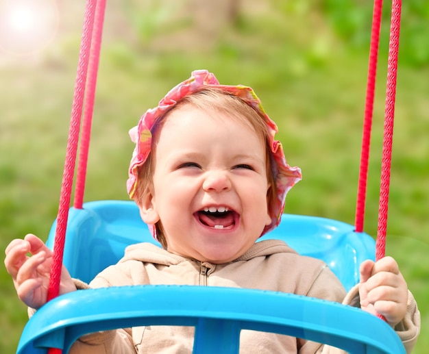 Il bambino cavalca su un'altalena e ride allegramente