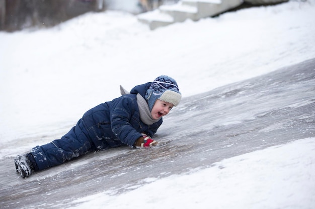 Il bambino cavalca su uno scivolo di ghiaccio Ragazzo allegro in inverno