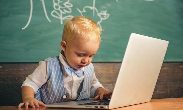 Il bambino cerca informazioni sugli utenti dei social network con un computer portatile a scuola