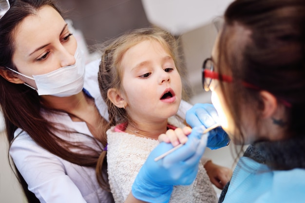 Il bambino che aiuta un dentista esamina un paziente