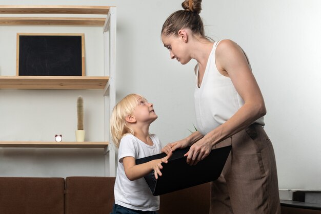 Il bambino chiede un laptop a sua madre. Ragazzo che prova a prendere il portatile della mamma.