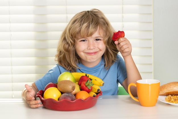 Il bambino con i frutti di estate della fragola il bambino mangia le verdure sane dell'alimento biologico con le vitamine corrette