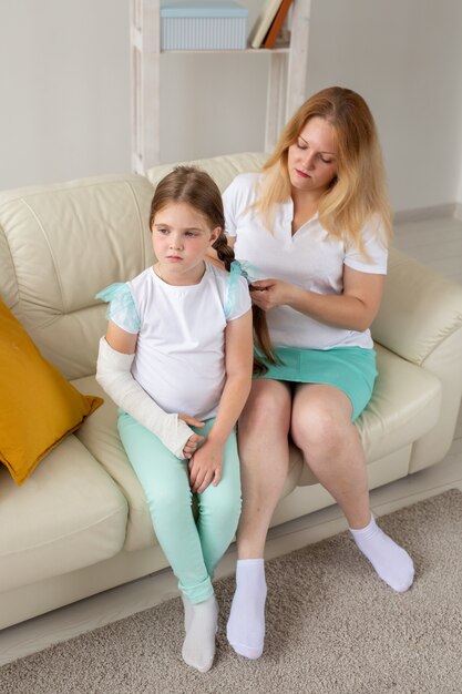 Il bambino con il braccio rotto e il gesso trascorrono del tempo a casa con la madre. Malattie infantili, un positivo