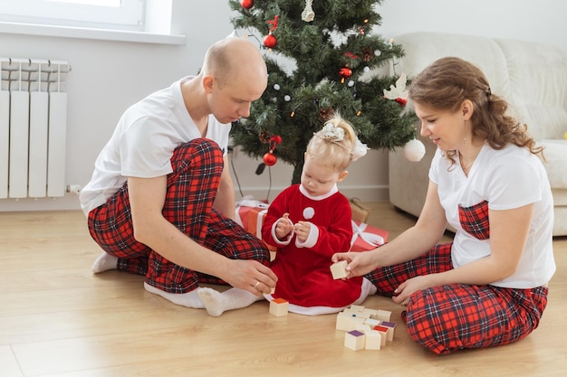 Il bambino con impianto cocleare gioca con i genitori sotto la sordità dell'albero di Natale e innovando