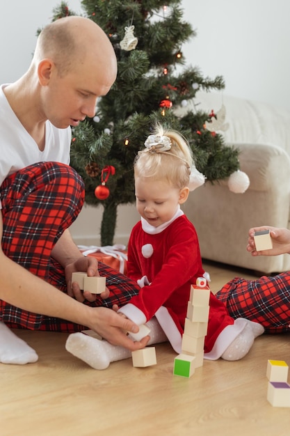 Il bambino con impianto cocleare gioca con i genitori sotto la sordità dell'albero di Natale e le tecnologie mediche innovative per gli apparecchi acustici