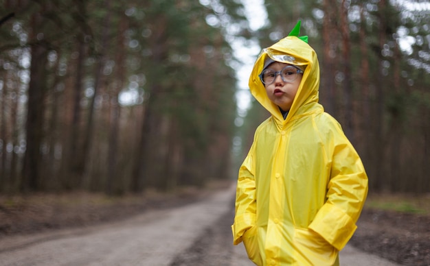 Il bambino con l'impermeabile giallo cammina nella foresta e si diverte