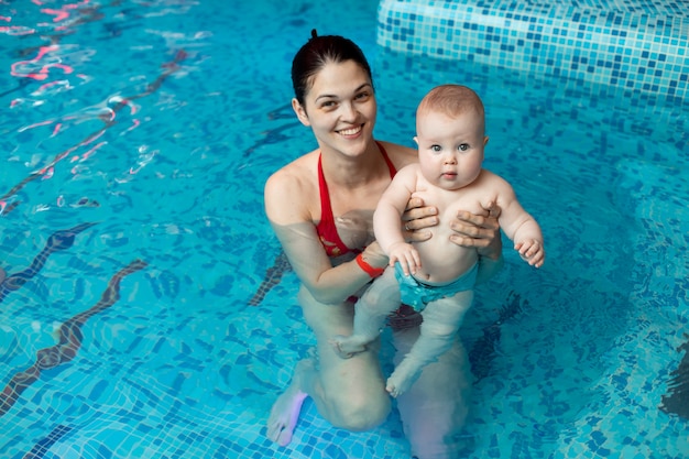 Il bambino con la mamma impara a nuotare in piscina