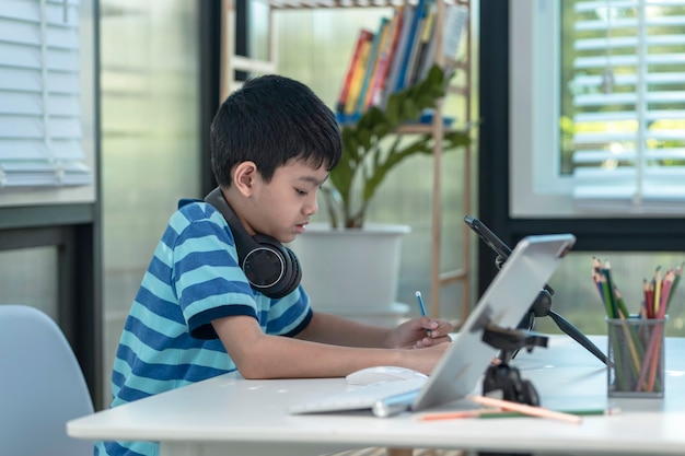 Il bambino con le cuffie sta usando un tablet e comunica su Internet a casa