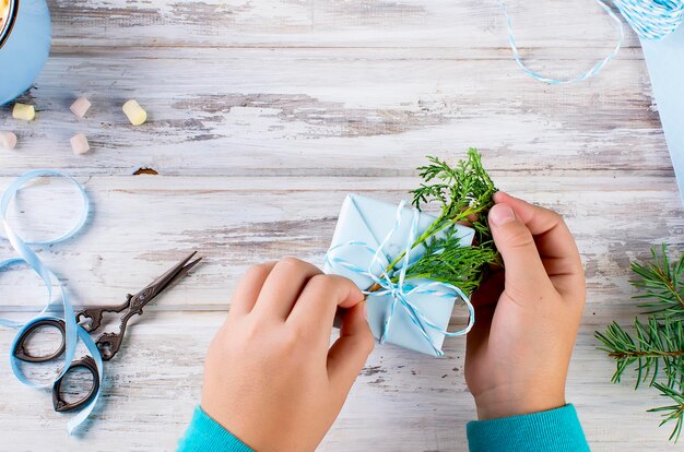 Il bambino confeziona e decora un regalo di Natale fatto a mano