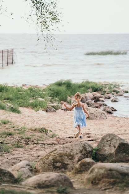 Il bambino corre lungo la riva del mare felice estate per un bambino foto verticale con un bambino che corre roccioso...