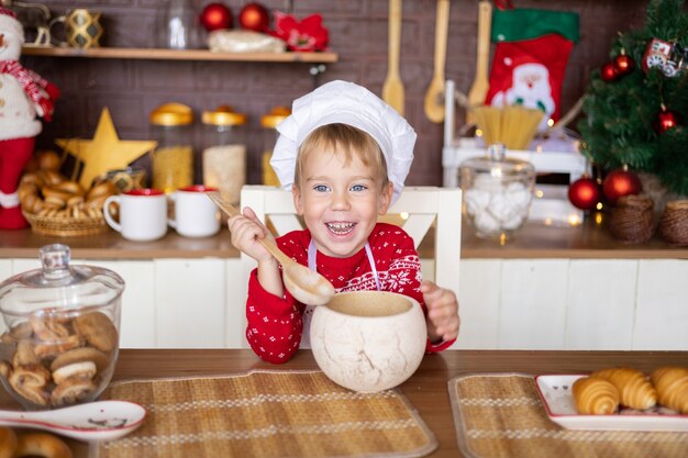 Il bambino cuoce i biscotti di natale nell'accogliente cucina di casa buon natale e concetto di vacanza di capodanno