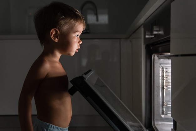 Il bambino curioso apre il forno caldo Concetto di sicurezza e possibili problemi con bambini incustoditi