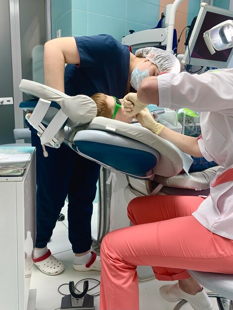 Il bambino dai capelli rossi è venuto dal dentista per un esame medico e infermiere per il trattamento della carie per l'igiene orale facendo una procedura dentale