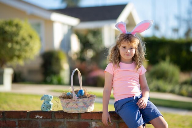 Il bambino dei bambini di Pasqua nelle orecchie del coniglietto tiene il ragazzo dell'uovo di Pasqua che caccia l'uovo di Pasqua