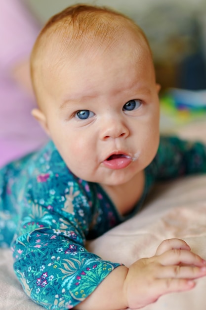 Il bambino di tre mesi è sdraiato sul letto e le tiene la testa.