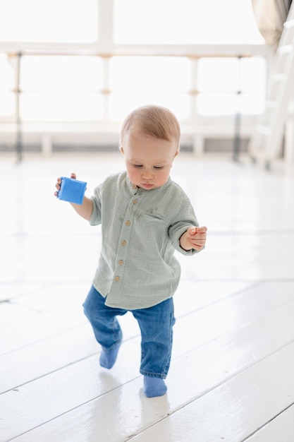 Il bambino di un anno gioca con i cubi sullo sfondo bianco dell'appartamento