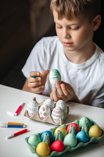 Il bambino dipinge le uova con colori diversi