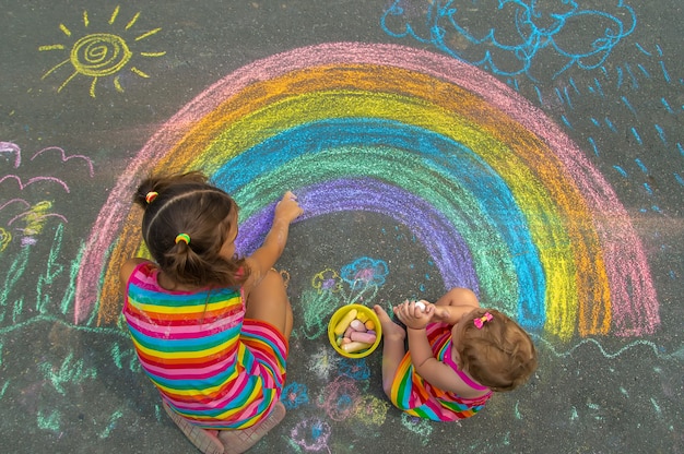 Il bambino disegna con il gesso sull'asfalto. Messa a fuoco selettiva. Ragazzo.