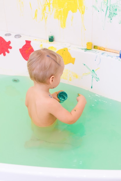 Il bambino disegna con le vernici nella vasca da bagno