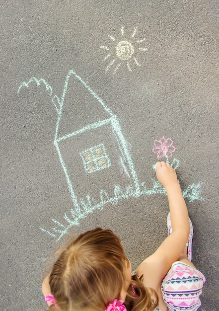 Il bambino disegna la casa con il gesso sull&#39;asfalto. Messa a fuoco selettiva