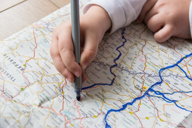 Il bambino disegna sulla mappa con la penna.