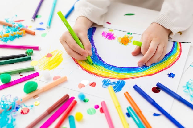 Il bambino disegna un arcobaleno con pennarelli