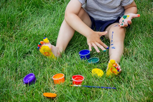 Il bambino disegna un motivo sulla gamba. Un disegno divertente con colori vivaci sul corpo. Messa a fuoco selettiva