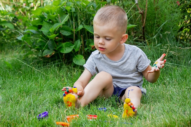 Il bambino disegna un motivo sulla gamba. Un disegno divertente con colori vivaci sul corpo. Messa a fuoco selettiva