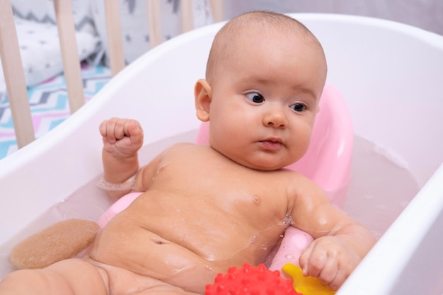 Il bambino divertente fa il bagno in bagno. Fare il bagnetto