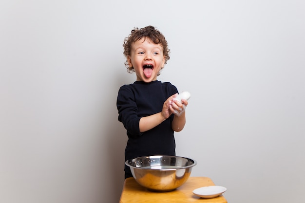 Il bambino divertente si lava le mani con sapone in una ciotola di acqua. le mani proteggono.