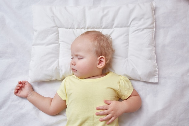 il bambino dorme su un cuscino bianco.