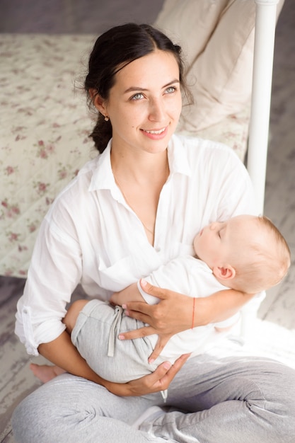 Il bambino dorme sul petto della madre. Giovane madre coccole bambino