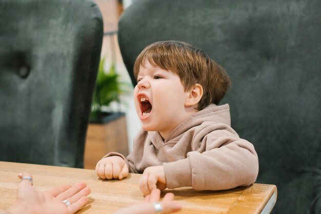 Il bambino è cattivo e dispettoso al tavolo di un bar seduto con sua madre