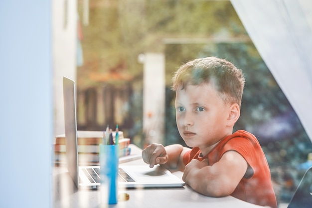 Il bambino è distratto dai suoi studi e guarda fuori dalla finestra