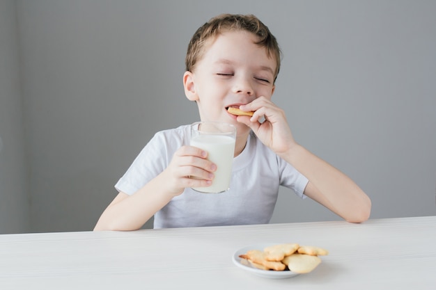 Il bambino è felice di mangiare biscotti fatti in casa con latte