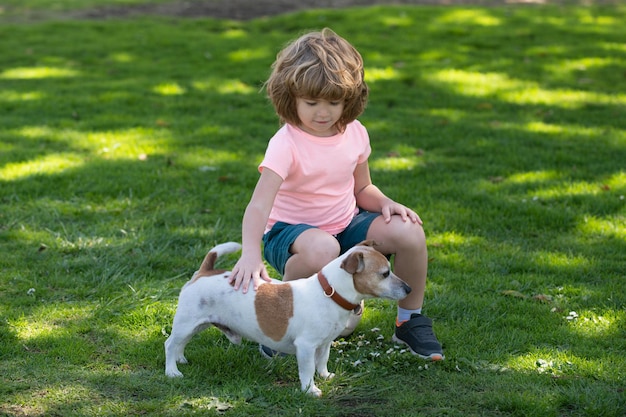 Il bambino e il cane felici la abbracciano con tenerezza sorridente bambino carino con cane che si rilassa sul bambino del parco ca