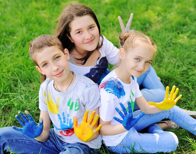 Il bambino è imbrattato di abiti dai colori vivaci che dipinge abiti sorridenti nel parco.