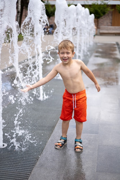 Il bambino è in piedi nella fontana un sacco di schizzi il bambino sta ridendo gioiosamente