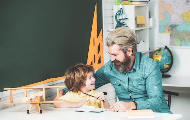 Il bambino e l'insegnante stanno imparando in classe sullo sfondo della scuola elementare dell'insegnante privato di lavagna...